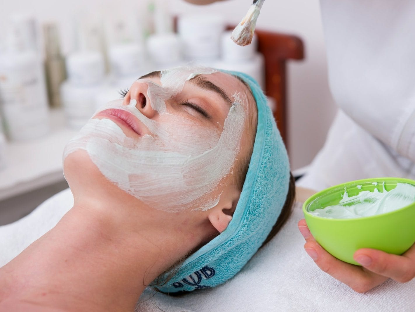 woman lying on blue towel with white cream on face